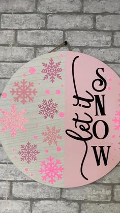 a pink and white sign hanging from the side of a brick wall with snow written on it