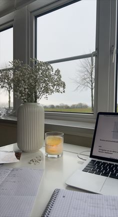 an open laptop computer sitting on top of a desk next to a glass filled with liquid