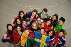 a group of people standing next to each other with flags on their shoulders and smiling at the camera