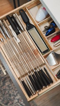 an organized drawer with knives, spoons and other kitchen utensils in it