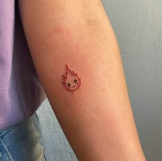 a woman's arm with a small fireball tattoo on the left side of her arm