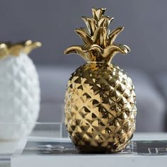 a gold pineapple sitting on top of a table next to two white vases