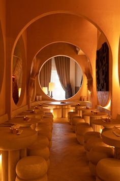 a room filled with lots of round tables and stools next to a large window