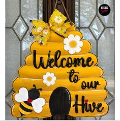 a welcome to our hive sign hanging on the front door with bees and daisies