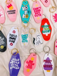 many different colored keychains with sayings on them sitting on a white sheet