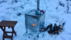 an old stove with a tea kettle on top in the snow next to a stool