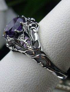 Natural Amethyst Ring Daisy Design#66 In Stock Size 6 Inspired by the Art Nouveau movement of the early 20th century, I now offer this lovely reproduction filigree ring in sterling silver. This gorgeous ring is set with a genuine/natural 1.5ct purple amethyst gemstone; which has a great shine and very good clarity. The round full cut purple amethyst gemstone is 8mm (5/16th of an inch) in diameter. The ring measures 12mm NS on the finger. The inside of the band is marked 925 for sterling. Notice Purple Intricate Design Promise Ring, Purple Promise Ring With Intricate Design, Purple Amethyst Ring With Intricate Design For Promise, Purple Amethyst Promise Ring With Intricate Design, Ornate Amethyst Purple Ring, Ornate Round Purple Amethyst Ring, Ornate Purple Amethyst Ring, Ornate Purple Ring For Anniversary, Intricate Design Purple Amethyst Ring