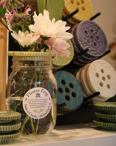 flowers in a mason jar sitting on a table next to buttons and other crafting supplies