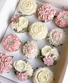 the cupcakes are decorated with pink and white frosting flowers in a box