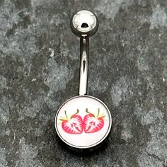 a pair of red cherries on a white belly button navel bar with black background