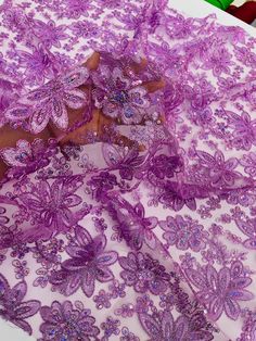 purple lace with flowers and butterflies on a white tablecloth, ready to be sewn