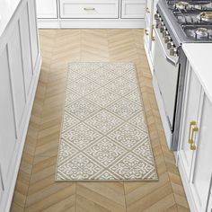 a kitchen with white cabinets and wood flooring on the walls, along with an area rug that looks like herringbones