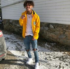 a young man standing next to a parked car in front of a house with snow on the ground