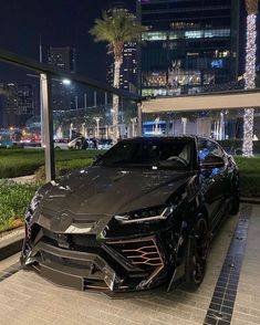 a black sports car parked in front of a tall building with palm trees on the other side