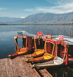 several boats are docked on the water with mountains in the background