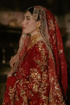 a woman in a red and gold bridal gown with her hair combed back