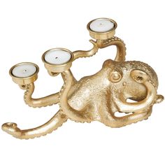 a gold octopus candle holder with two candles in it's mouth and one on its back