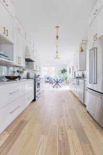 a kitchen with white cabinets and stainless steel appliances, along with hardwood flooring in the middle