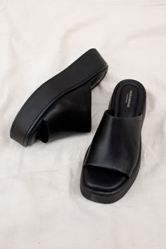 Vagabond Shoemakers Courtney platform slides. It is all about the characteristic flared outsole that makes this pool slide style the ultimate sandal of the season. The simple slip-on upper, made from black leather, is grounded by tonal flatform soles measuring 50 mm. Details include padded insoles and square toes. Heel height 50mm. Cow leather upper, Pu outsole, textile lining, cow leather inner sole. This style is made by Gia Ding Shoes Co. Ho Chi Minh City, Vietnam. 5134-001-92 / 5334-601-92 P Platform Black Slides, Platform Slides Outfit, Cute Black Shoes, Black Platform Slides, Slip In Shoes, Platform Shoes Outfit, Chunky Slides, Summer Shoes Women, Slide On Shoes