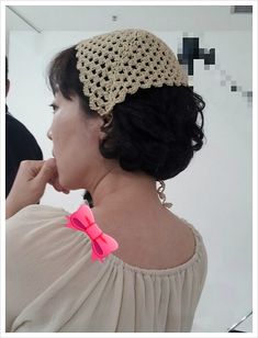 a woman wearing a crochet hat with a pink bow on her head and neck