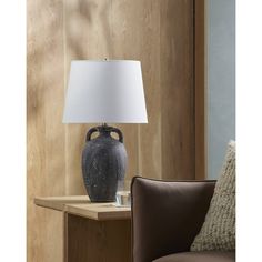 a black vase sitting on top of a wooden table next to a brown leather chair