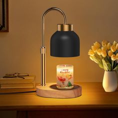 a lit candle sits on a wooden table next to a vase with flowers and books