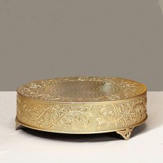 an ornately decorated gold plate on a white table