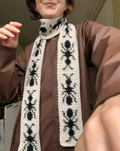 a woman is wearing a scarf with black and white designs on it, as she poses for the camera