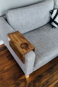 a wooden table sitting on top of a gray couch next to a black and white pillow