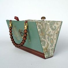 a green and brown purse sitting on top of a white table