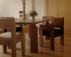 a dining room table with chairs and a vase filled with flowers on top of it