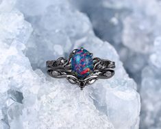 a ring with an opalite surrounded by leaves on top of some ice crystals