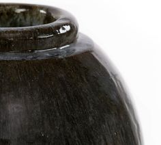 a black vase is sitting on a white surface