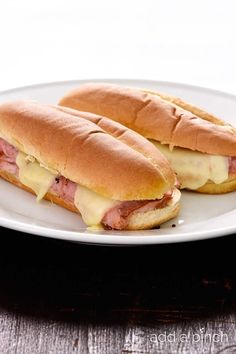 two sub sandwiches sitting on top of a white plate