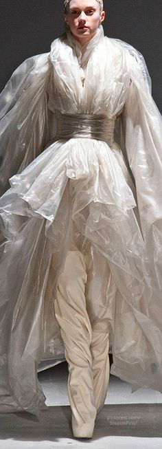 a woman is walking down the runway in a white dress with long veils on her head