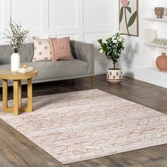 a living room with a couch, coffee table and rug on the hardwood flooring