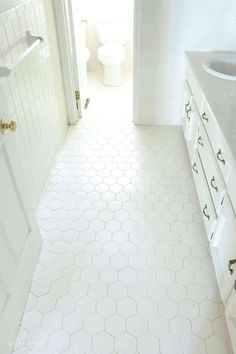 a white bathroom with hexagonal tile flooring