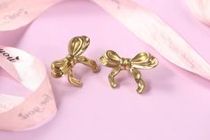 pair of gold bow clip earrings on pink background