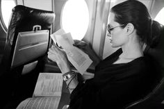 a woman sitting in an airplane reading a book