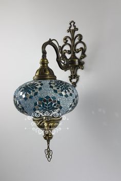 a blue and white lamp hanging from the side of a light fixture on a wall