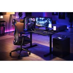 a computer desk with two monitors and a gaming chair in front of it at night