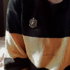 a person wearing a black and white striped sweater with a crest on the front pocket