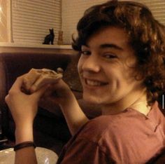 a young man sitting on top of a couch holding a hot dog in his hand