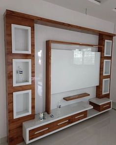 a white and wooden entertainment center in a living room with shelves on each side, tv mounted to the wall