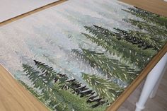 a close up of a rug on the floor with pine trees in the foreground