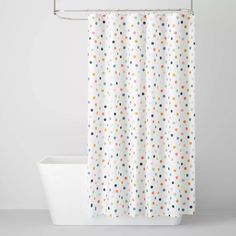 a white shower curtain with multicolored polka dots on it in front of a bathtub