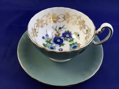 a tea cup and saucer decorated with blue flowers