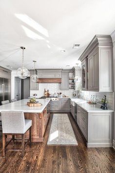 a large kitchen with wooden floors and gray cabinets