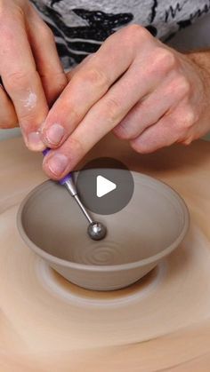 a person using a spoon to make a bowl on a potter's pottery wheel