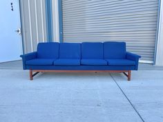 a blue couch sitting on top of a cement floor next to a garage door with roller doors in the background